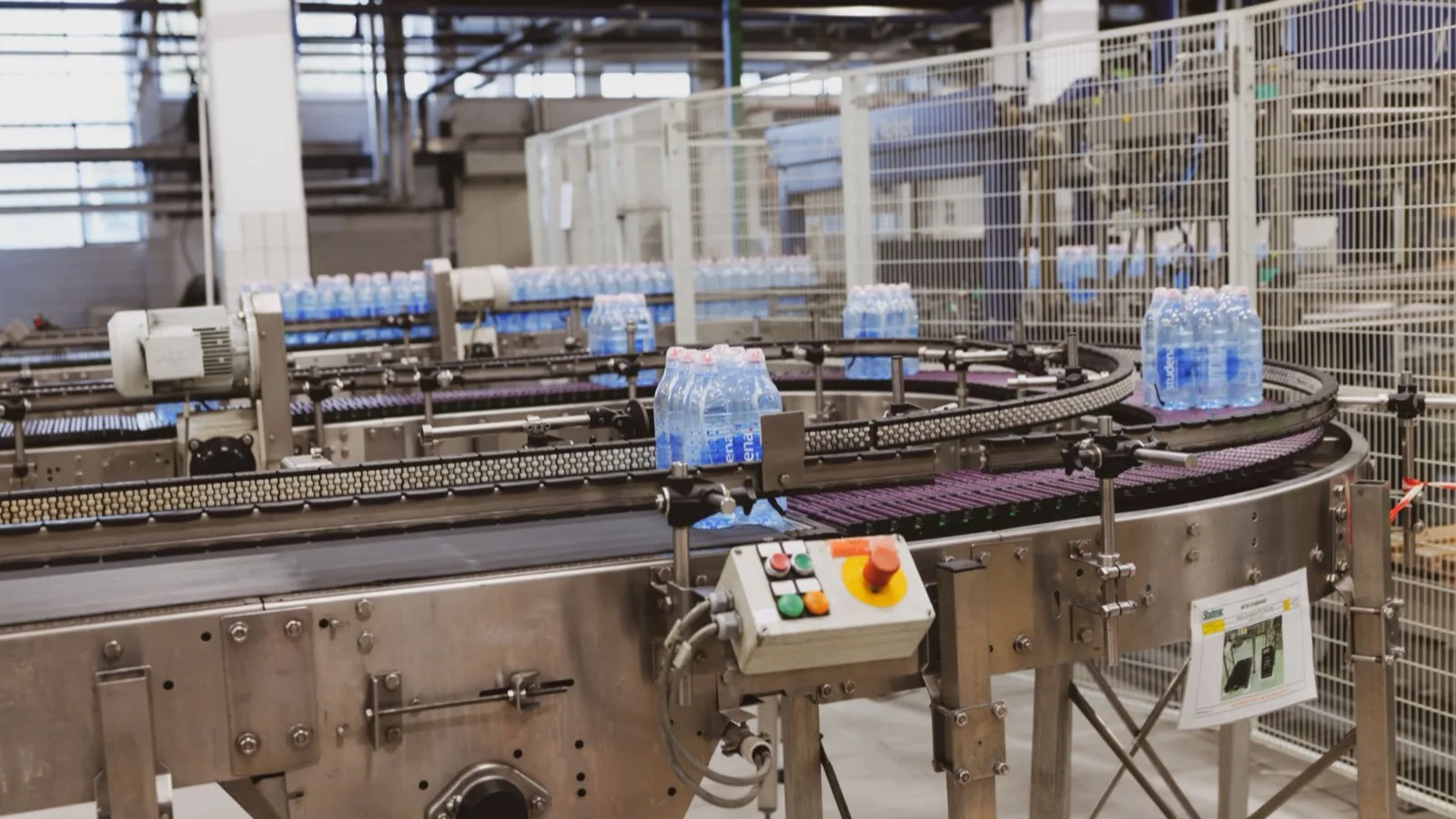 Water bottles being processed on an automated conveyor in a modern factory setting.