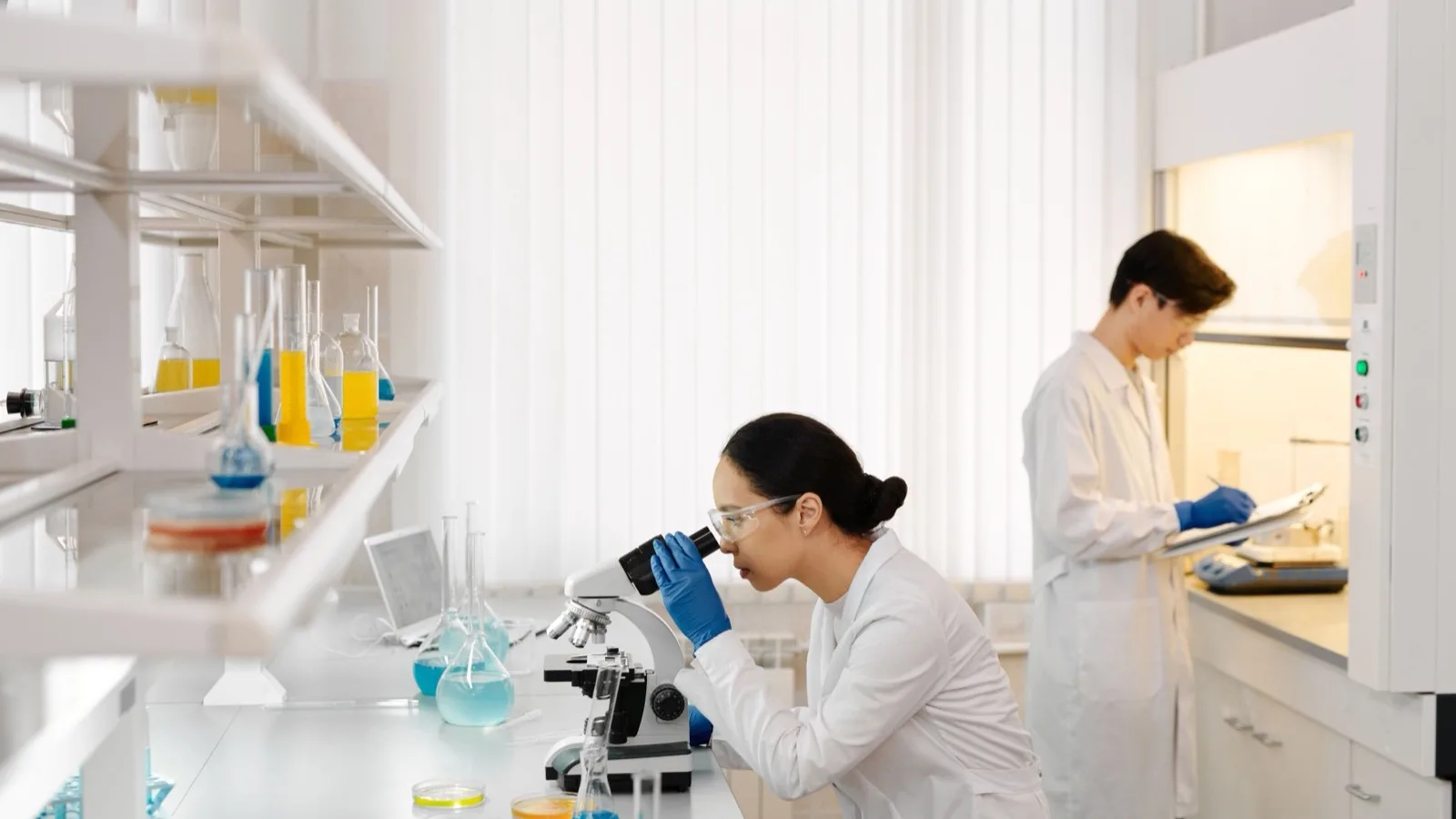 Two scientists working in a well-equipped laboratory with microscopes and test tubes.