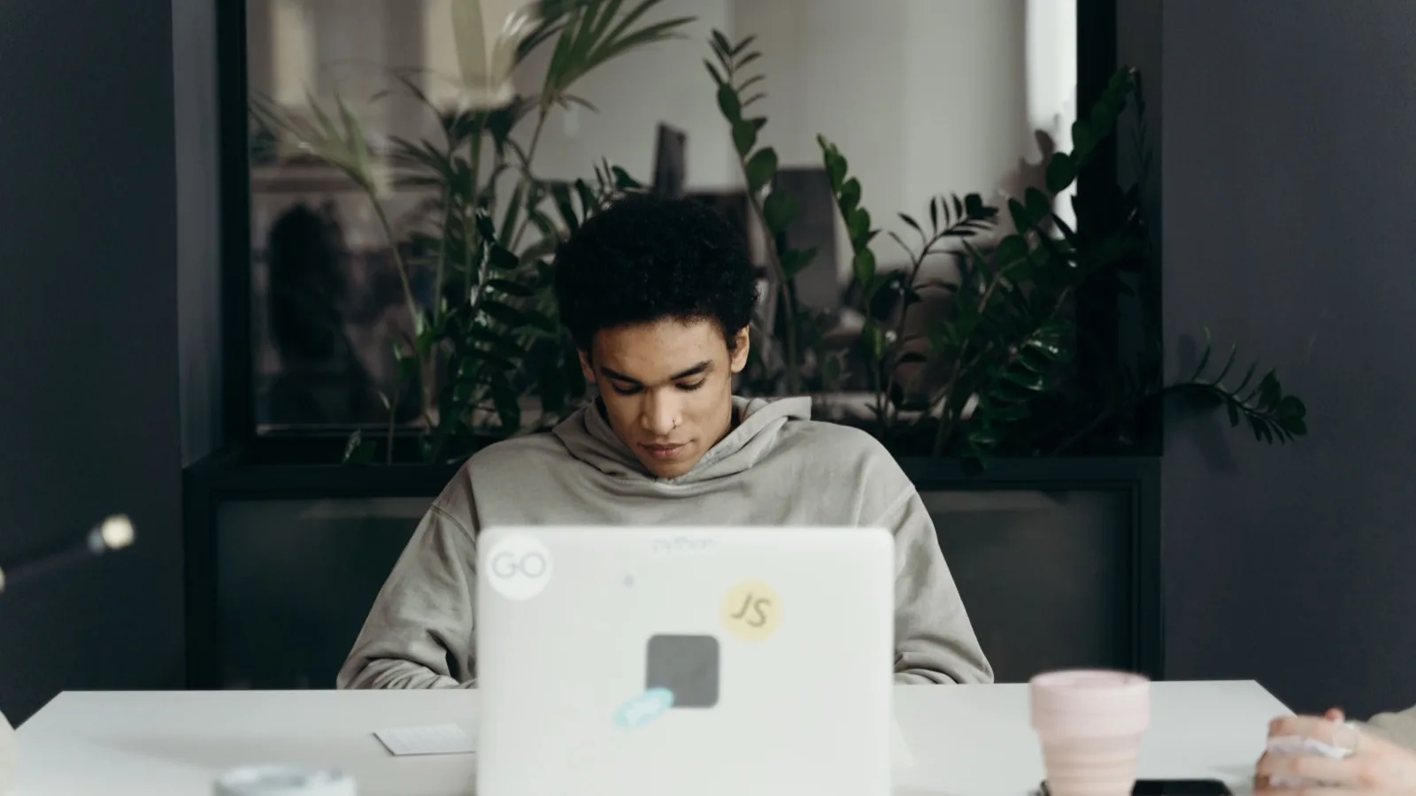 Focused young professional working on a laptop in a modern office environment.